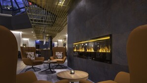Un área de estar moderna con sillones de cuero, una mesa redonda de madera y una chimenea empotrada en la pared.