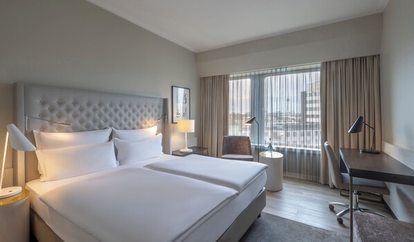 A hotel room with a large bed, two bedside tables, a desk, and a chair.