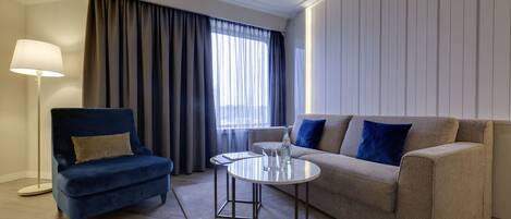 A modern living room with a blue armchair, a beige sofa, a round coffee table, and a floor lamp.