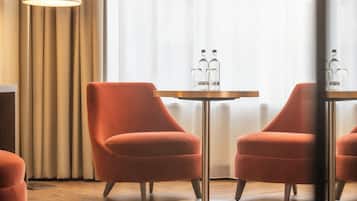 Una habitación moderna con dos sillones anaranjados, una mesa redonda con dos botellas, una lámpara de pie y un radiador.