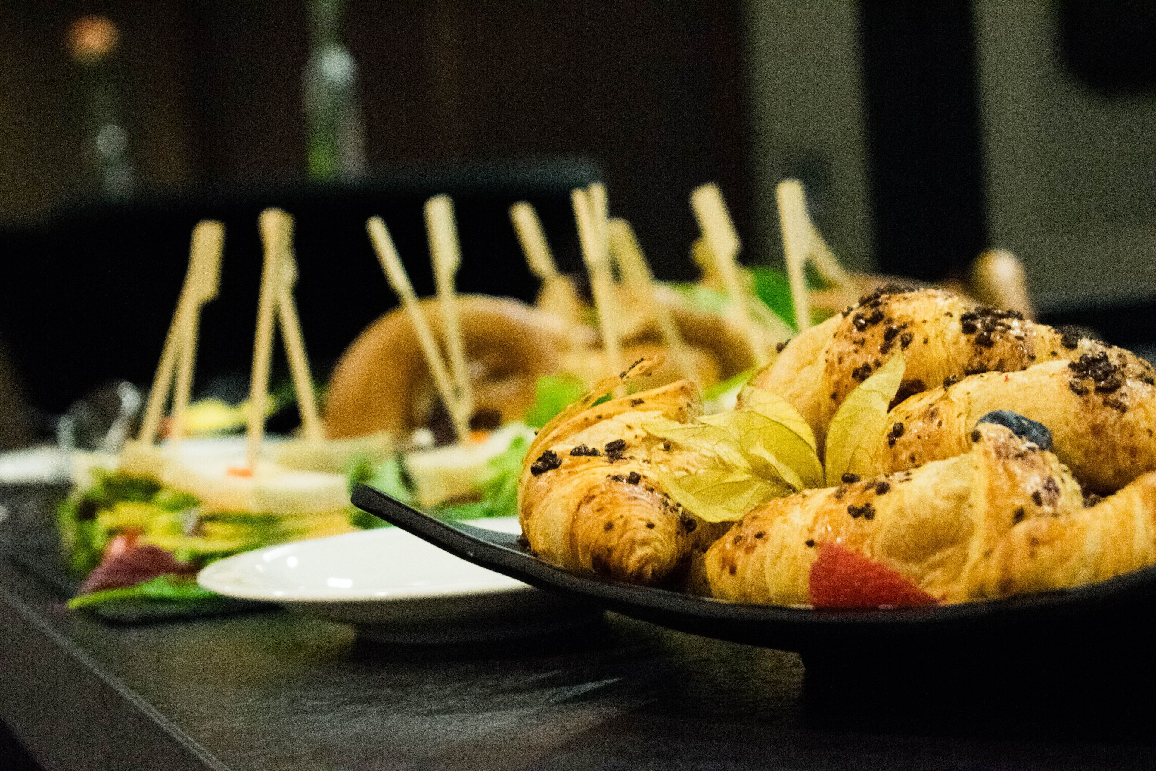 A buffet table with various food items including pastries and salads.