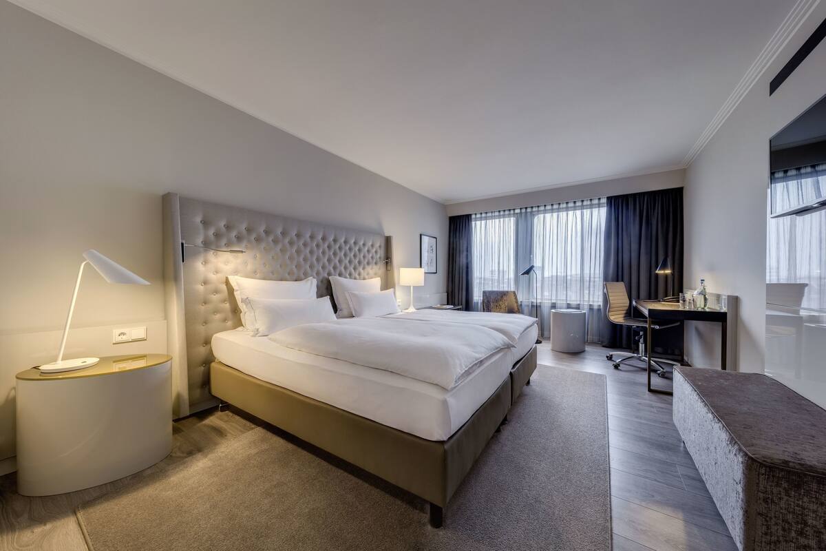 Una habitación de hotel moderna con una cama grande, un escritorio y una silla.