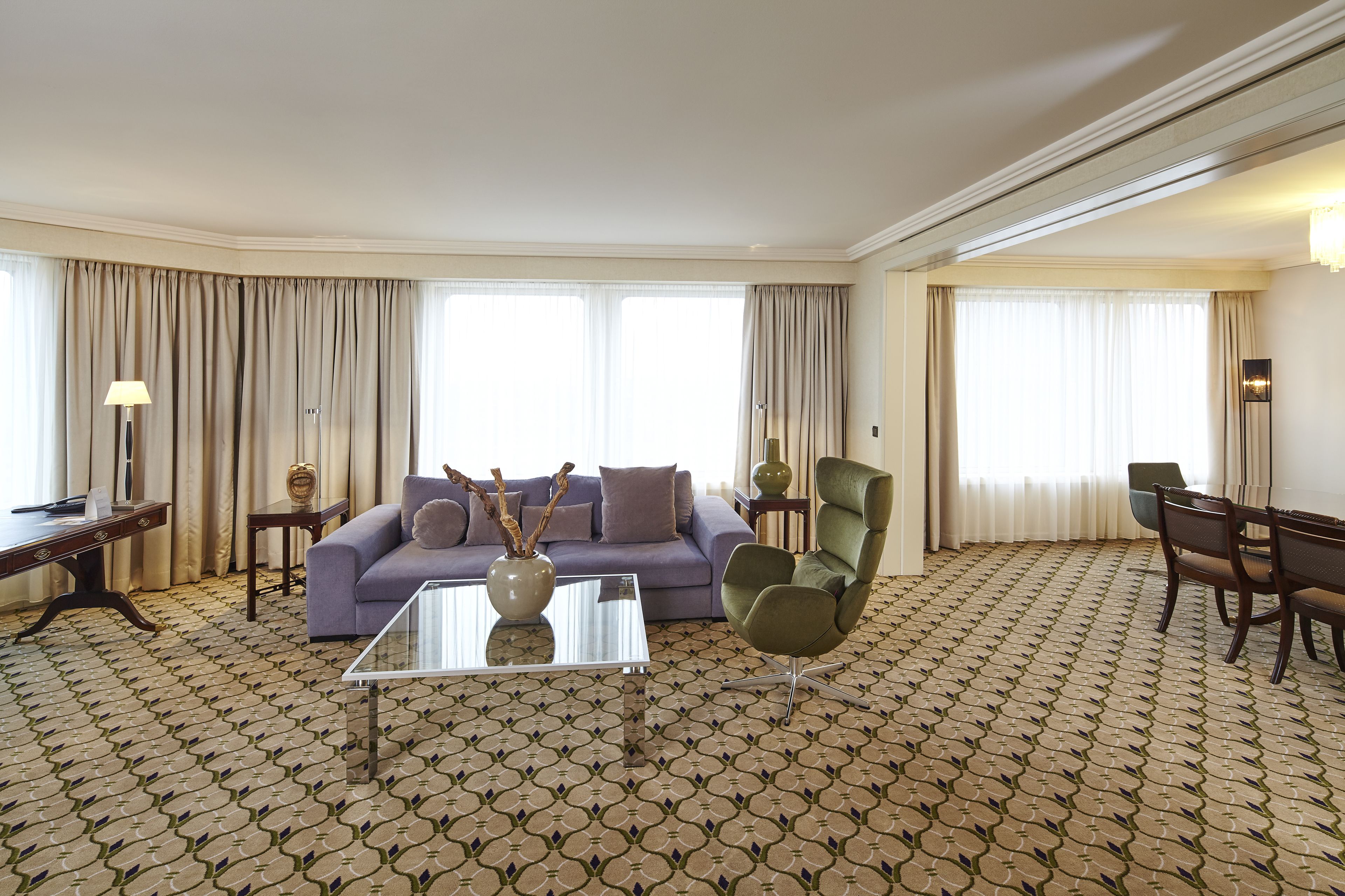 Un salon moderne avec un canapé, des fauteuils, une table basse et un tapis à motifs.