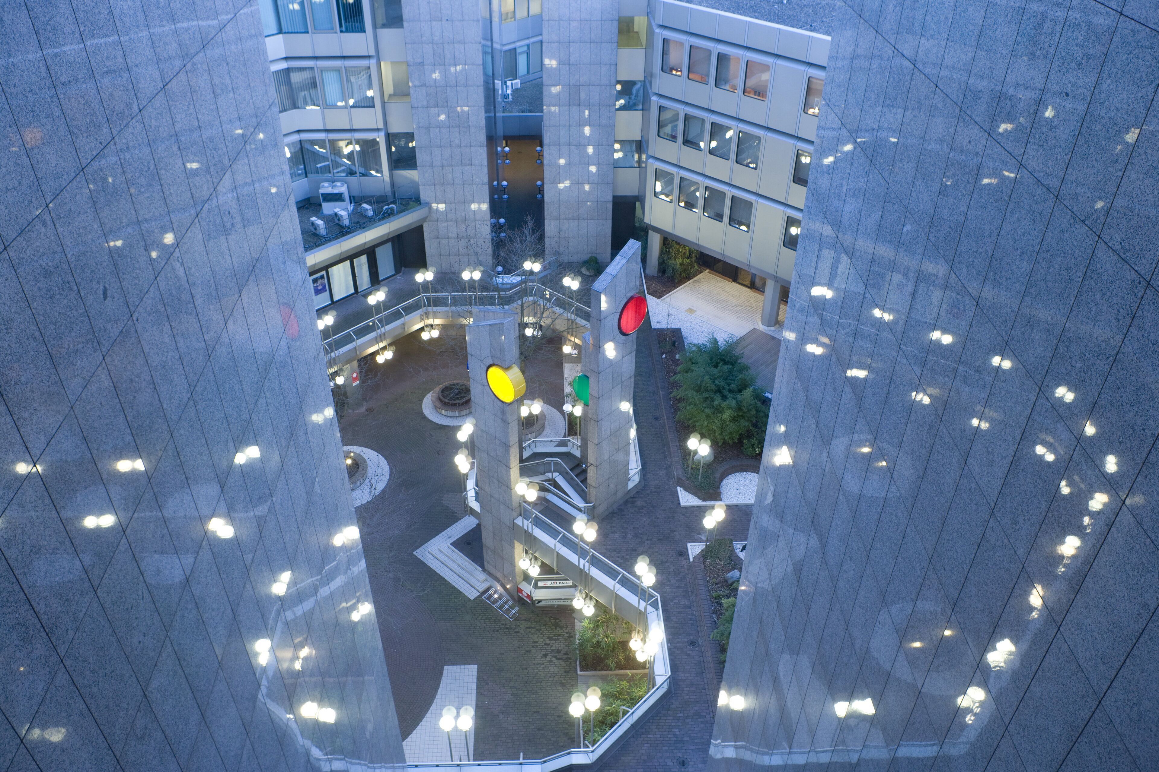 Un edificio de gran altura con un patio central que presenta una glorieta, escaleras y un espacio verde con plantas.