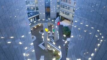 Un edificio de gran altura con un patio central que presenta una glorieta, escaleras y un espacio verde con plantas.