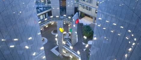 Un edificio de gran altura con un patio central que presenta una glorieta, escaleras y un espacio verde con plantas.