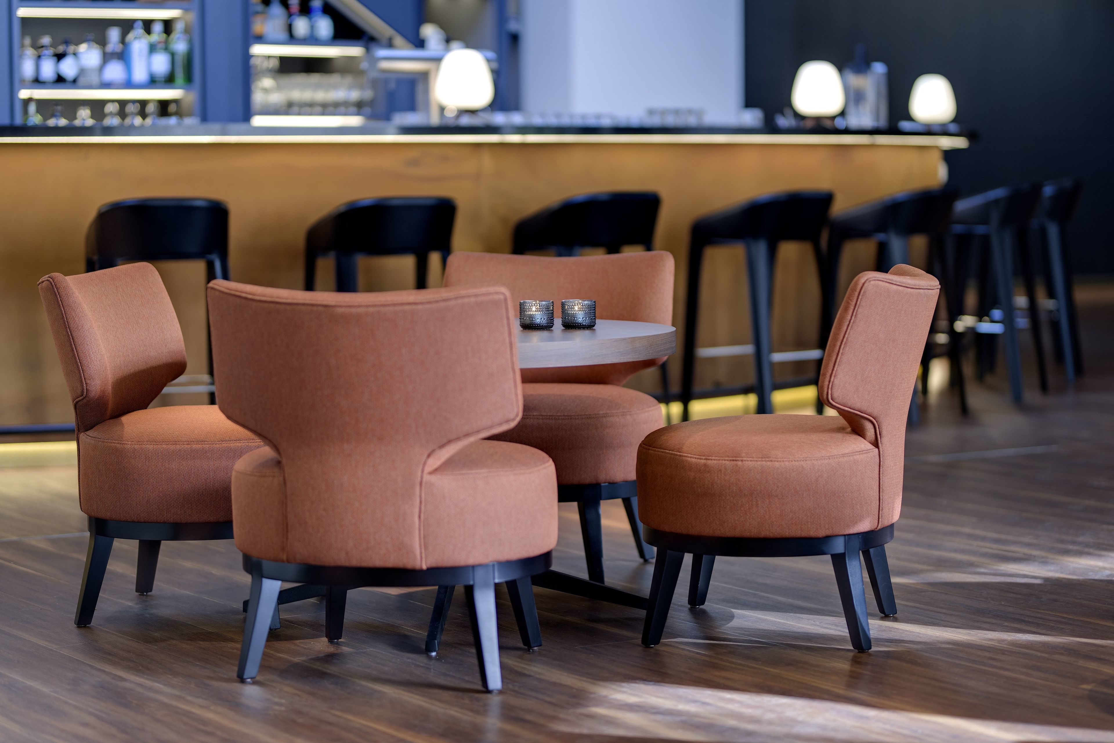 A modern bar area with a round table and four cushioned chairs.