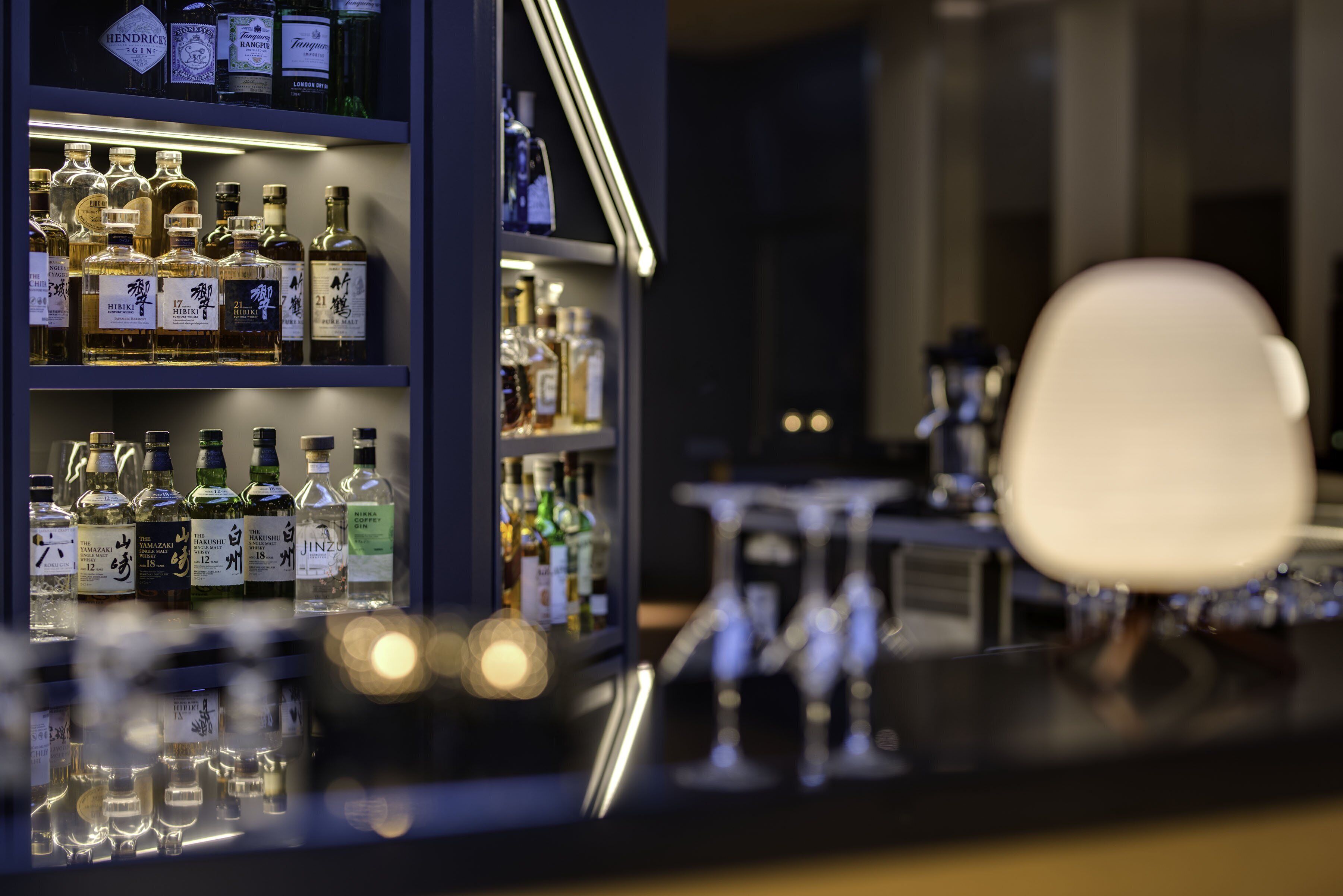 Zona de bar con estantes llenos de botellas de licores y vasos.