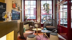 A modern lounge area with seating, a coffee table, and a large window with a view of the street. - Hotel Mercure Wien Zentrum (Vienna)