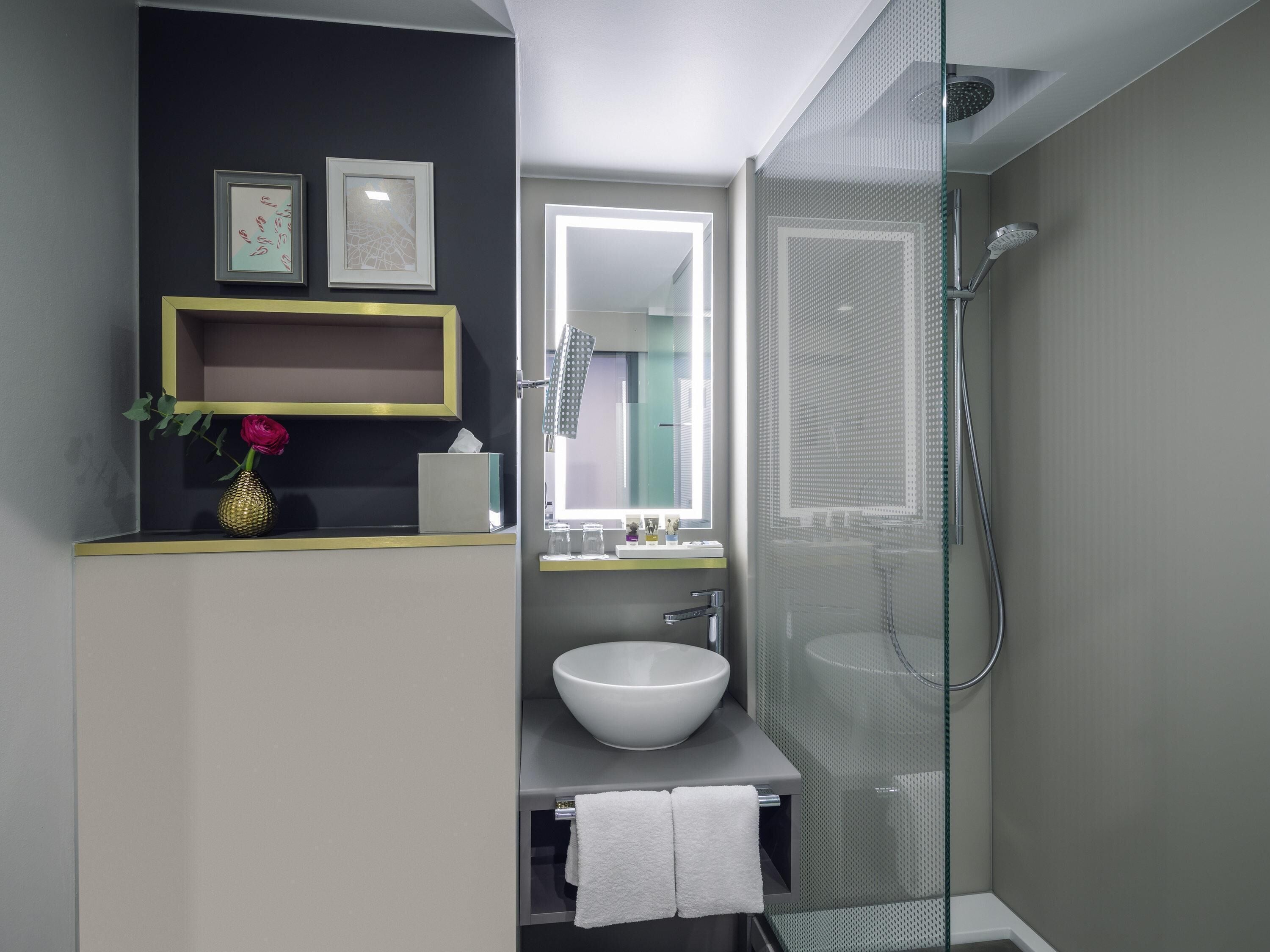 Un bagno moderno con box doccia in vetro, un lavandino bianco e uno specchio sopra.