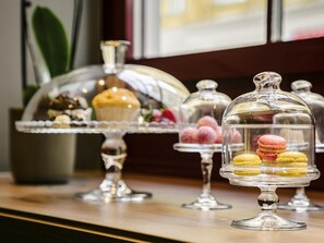 A dessert display with macarons and a muffin on a glass stand. - Hotel Mercure Wien Zentrum (Vienna)