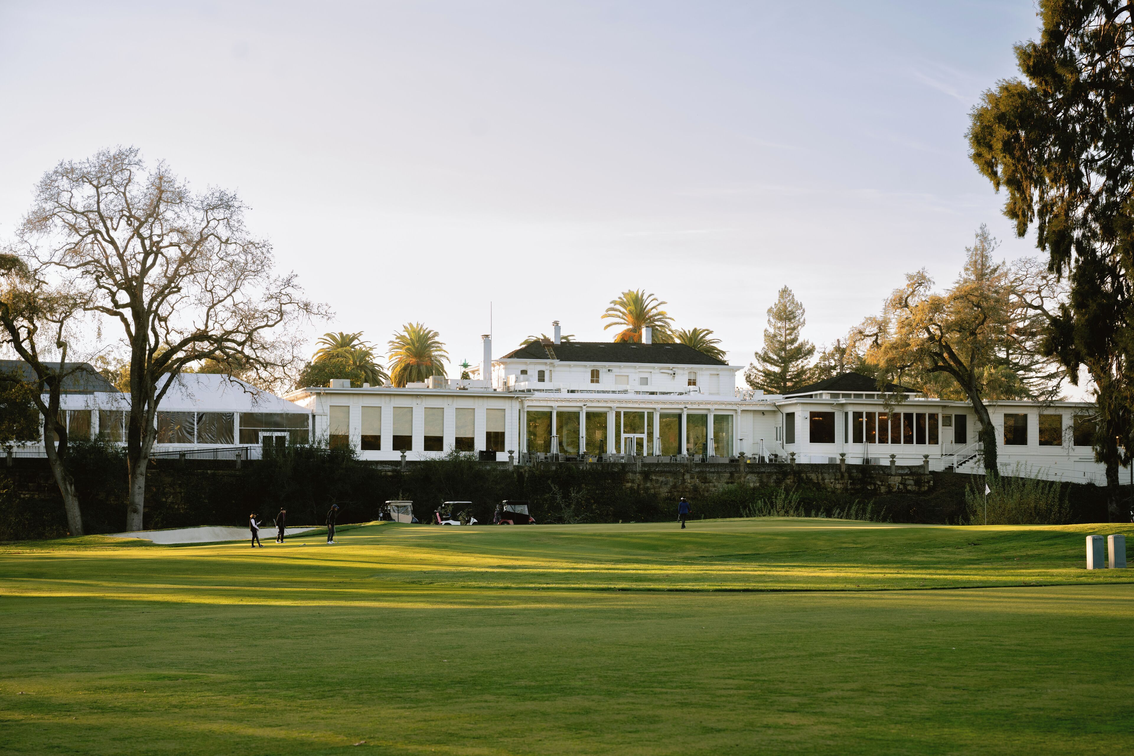 A large, white building with a symmetrical facade, surrounded by a well-maintained lawn and trees.