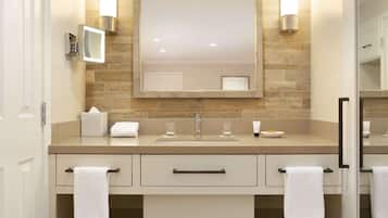 Une salle de bain moderne avec un comptoir de couleur beige, un grand miroir et deux serviettes suspendues à des porte-serviettes.