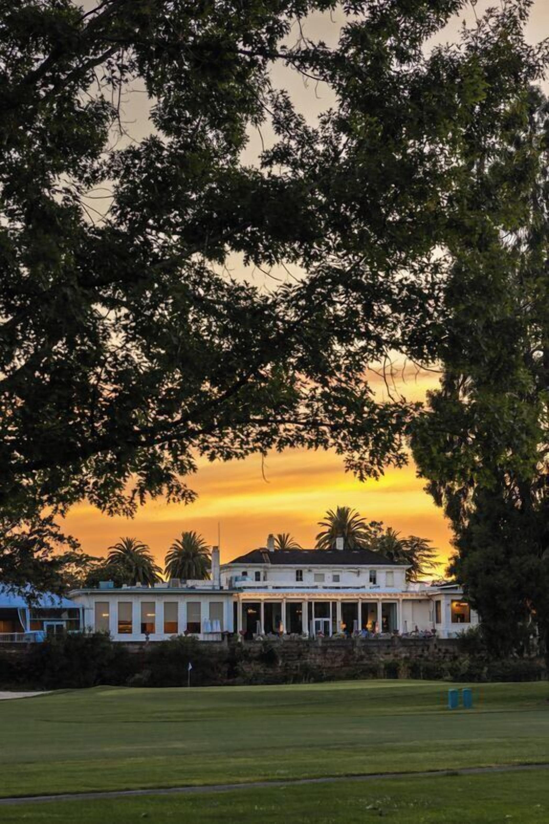 A building with a large lawn in front, surrounded by trees.