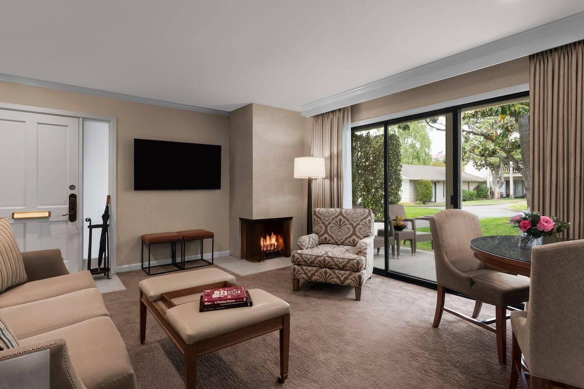 A living room with a fireplace, a flat-screen TV, and a view of the outdoors.