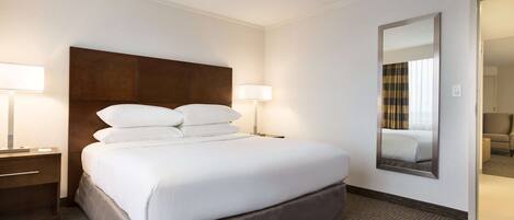 A hotel room with a large bed, two bedside tables with lamps, a large mirror, and a carpeted floor.