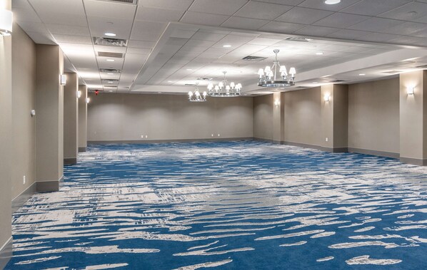 A large, empty conference room with a blue carpet, recessed lighting, and chandeliers. - DoubleTree by Hilton New Bern Riverfront (New Bern)