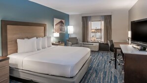 A hotel room with a large bed, a desk with a TV, a chair, a lamp, and a window with a view of a harbor. - DoubleTree by Hilton New Bern Riverfront (New Bern)