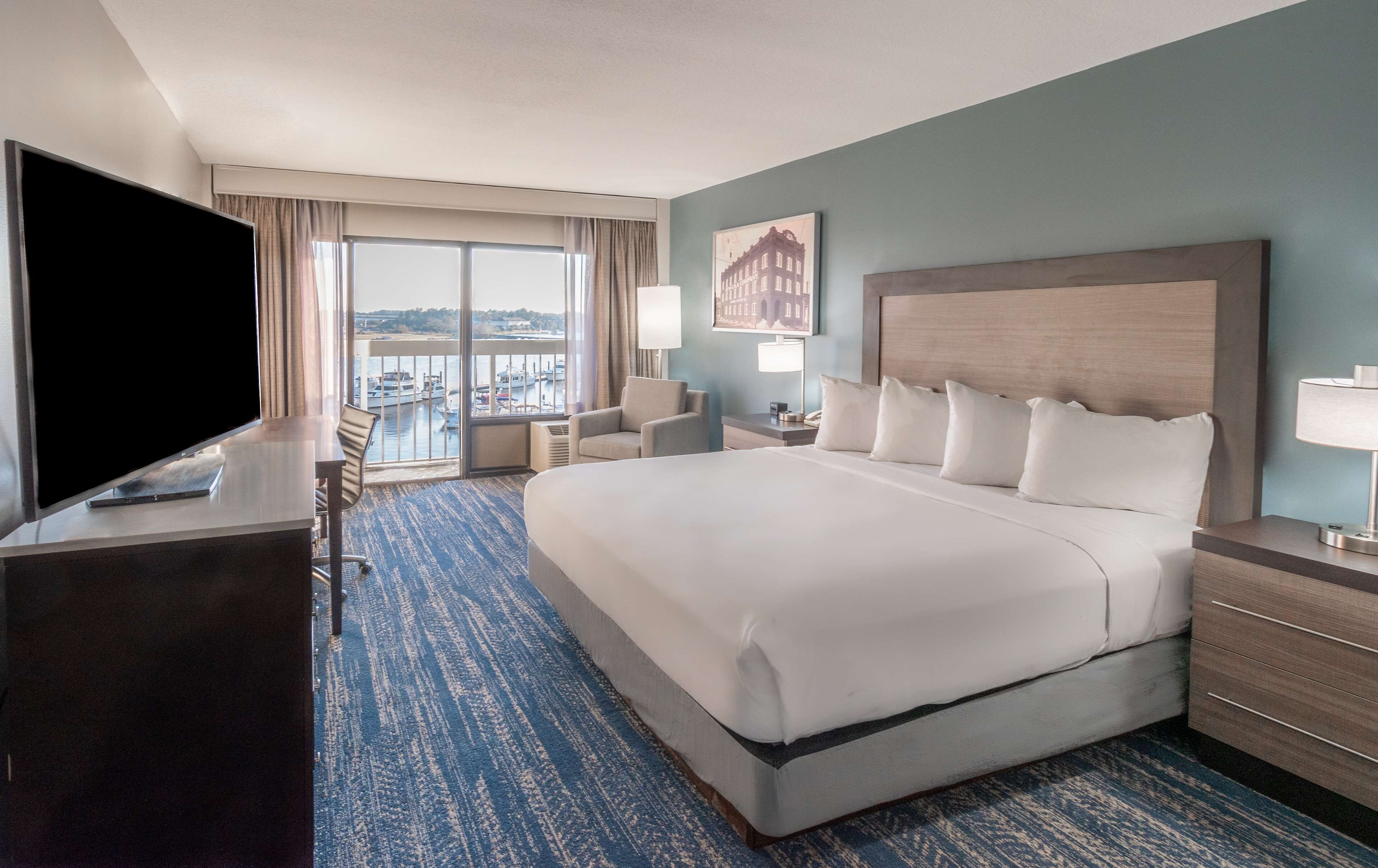 Une chambre d’hôtel avec un grand lit, une télévision, un bureau et une vue sur le port.