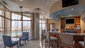 A hotel bar area with a pool view, bar stools, and a television. - DoubleTree by Hilton New Bern Riverfront (New Bern)