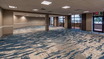 A spacious indoor area with a patterned carpet, large windows, and an exit sign.
