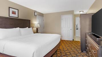 A hotel room with a large bed, a dresser, a television, and a patterned carpet.