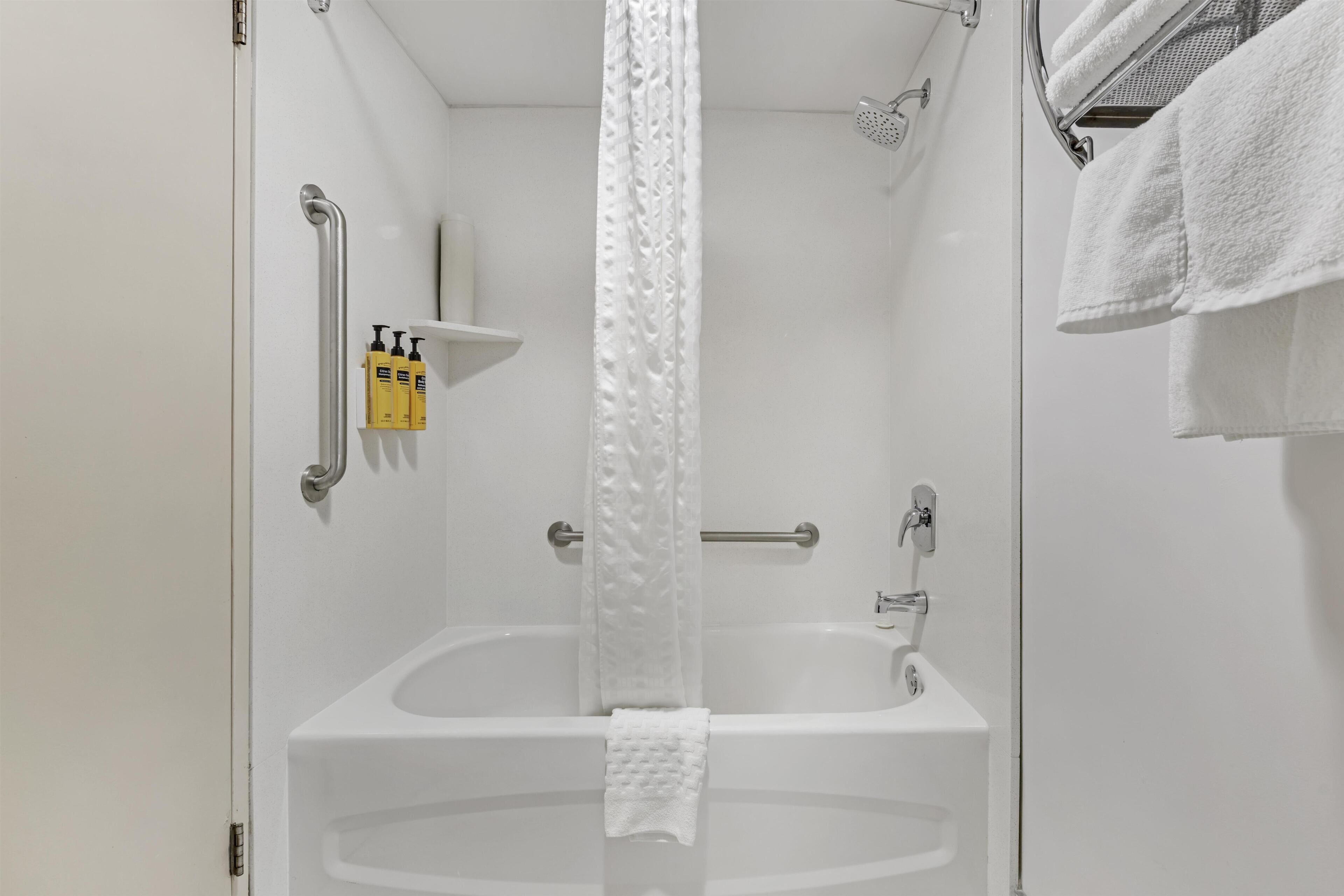Ein Badezimmer mit Badewanne, Dusche, Handtuchhalter und Ablage für Toilettenartikel.