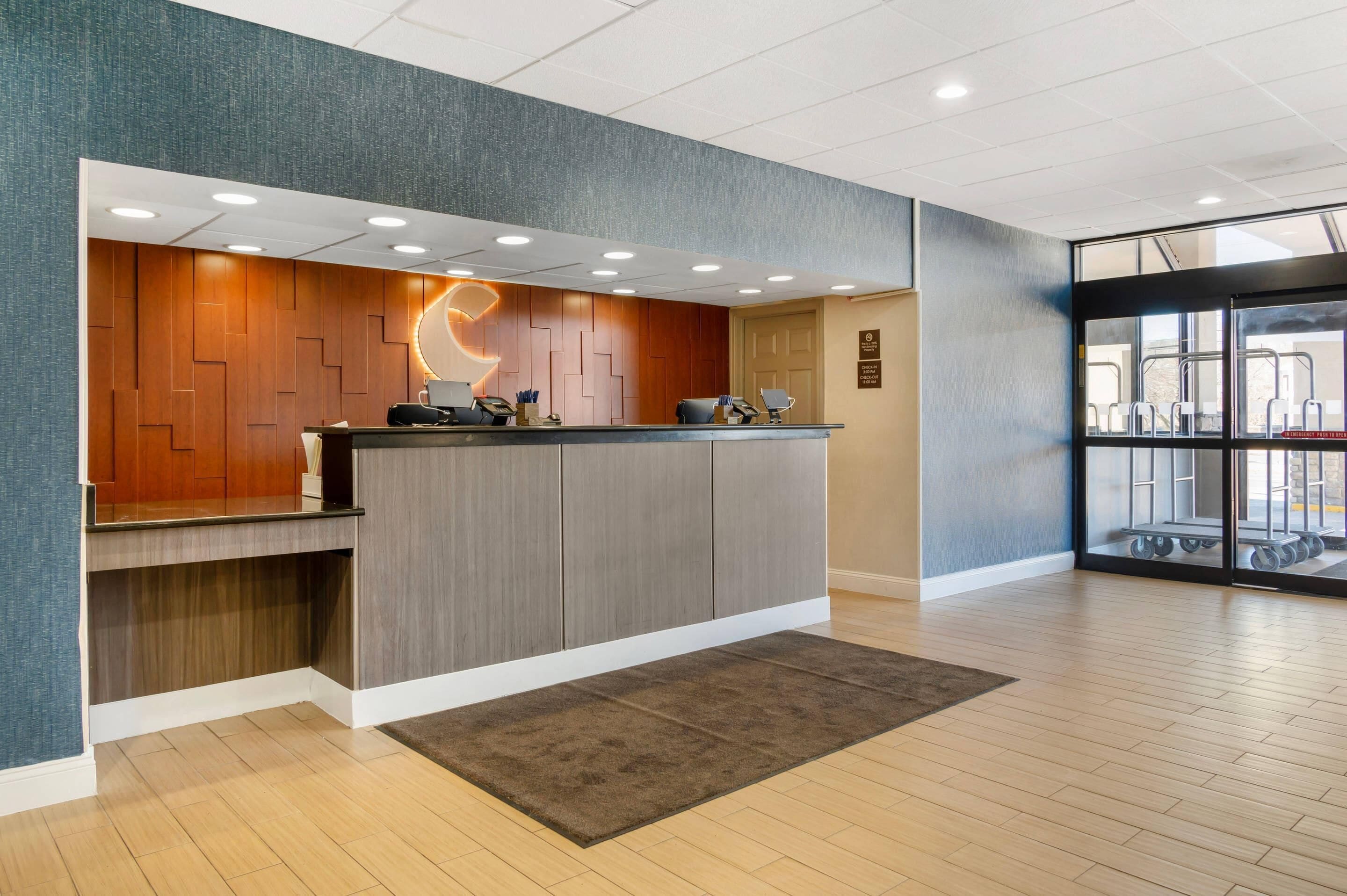 A reception area with a wooden panel wall, a reception desk, and a large window with a view of outdoor equipment.