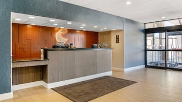 A reception area with a wooden panel wall, a reception desk, and a large window with a view of outdoor equipment.