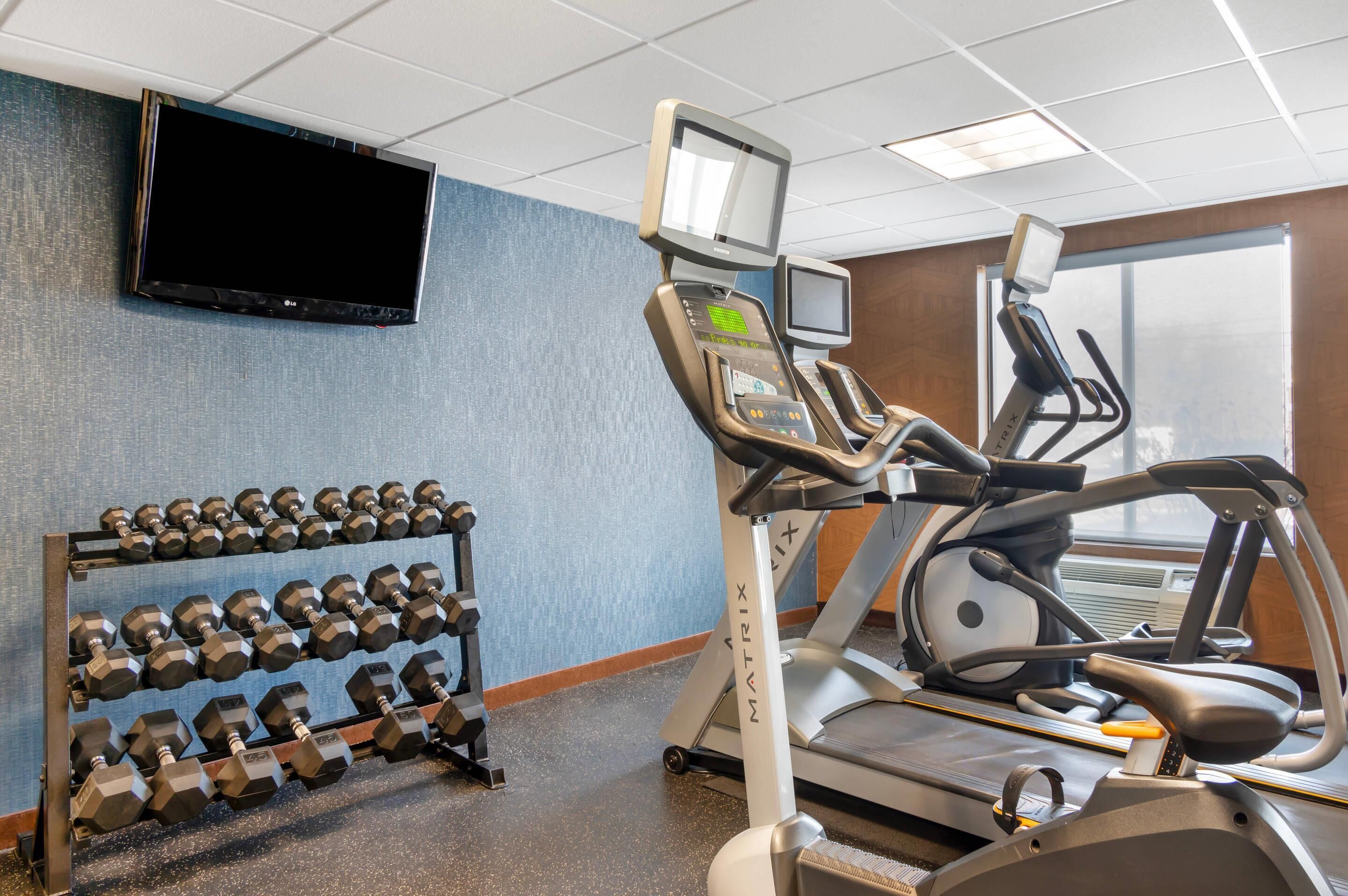 A gym with exercise equipment, including dumbbells, treadmills, and stationary bikes.