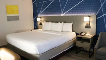 A hotel room with a large bed, two bedside tables with lamps, a chair, and a wall with a geometric pattern.