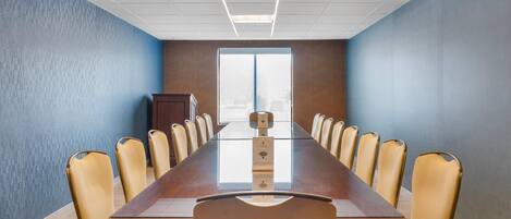 A conference room with a long table, beige chairs, and a cabinet.