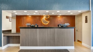 A reception desk with a wooden panel design, a crescent moon light fixture, and a check-in counter. - Comfort Inn & Suites Danbury-Bethel (Danbury)
