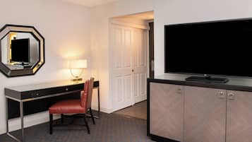 A hotel room with a desk, chair, TV, and wardrobe.
