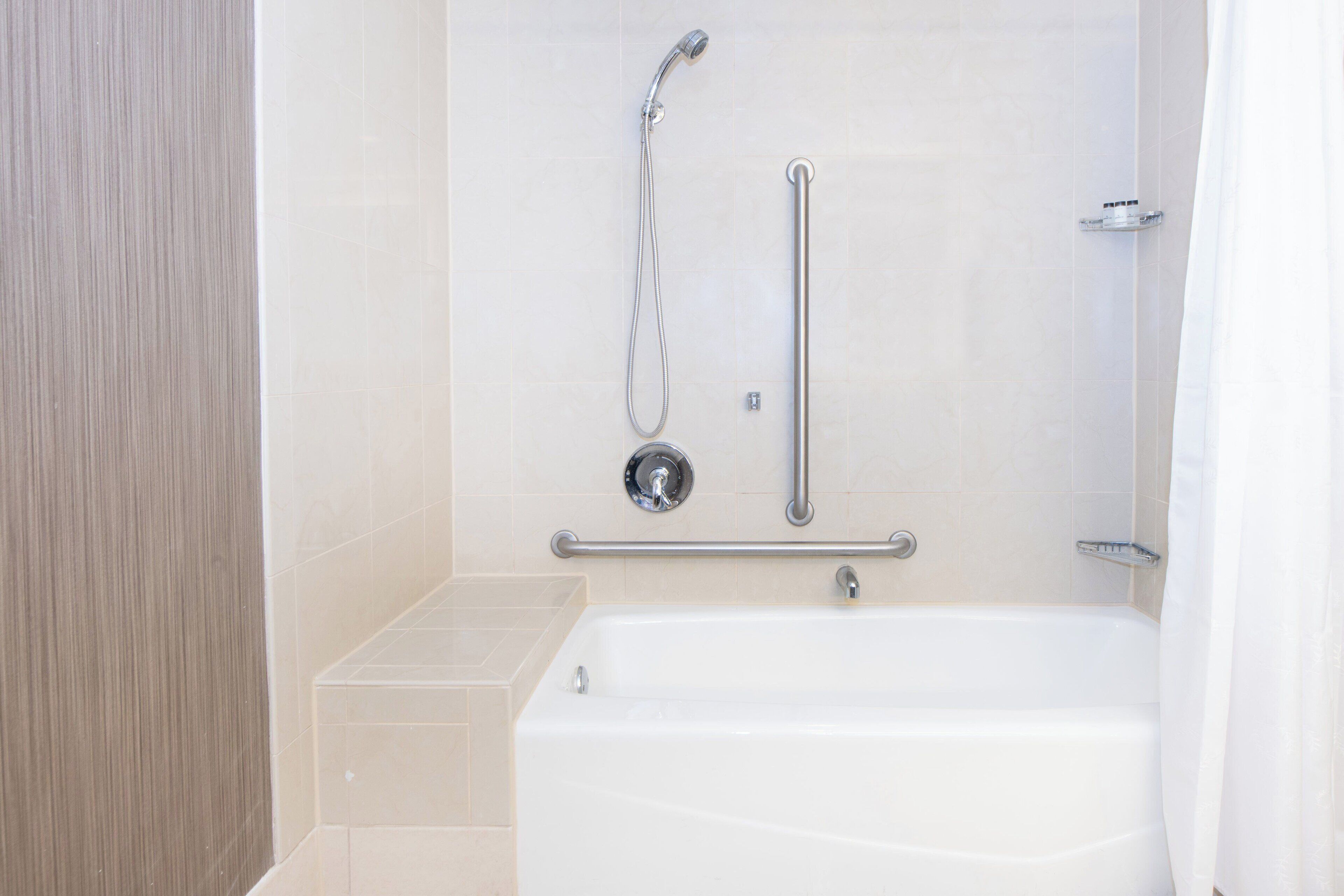 A modern bathroom with a bathtub, a shower with a handheld showerhead, and a grab bar.