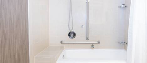 A modern bathroom with a bathtub, a shower with a handheld showerhead, and a grab bar.