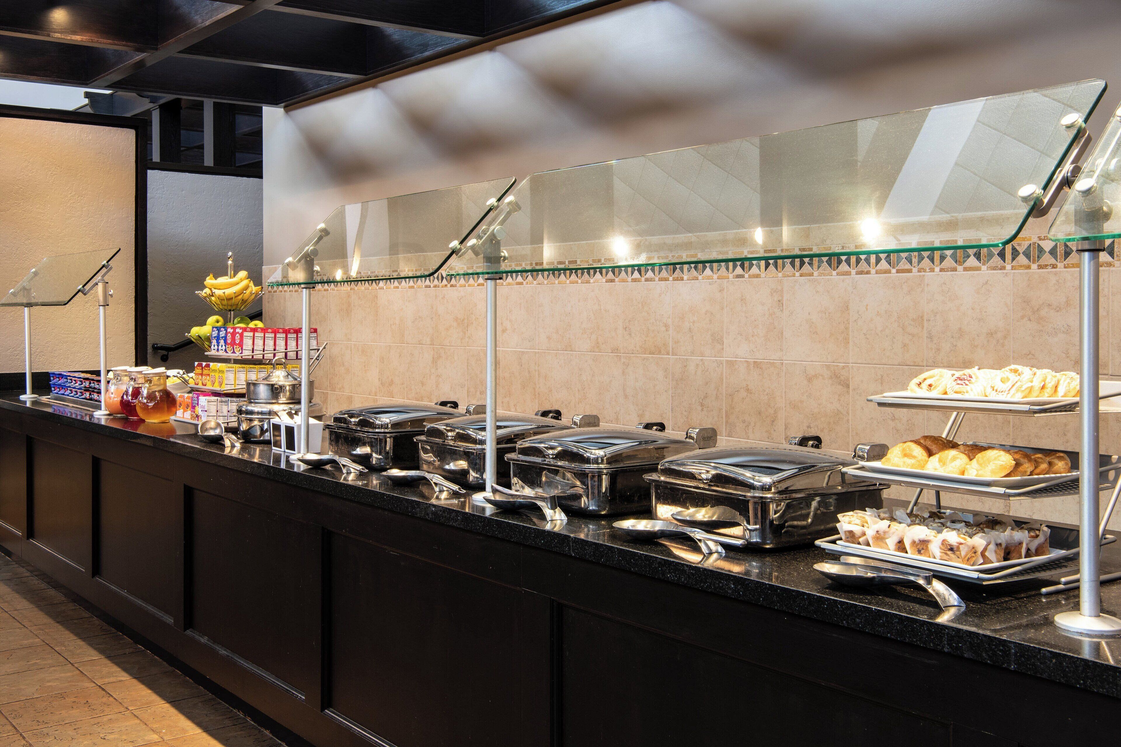 Mostrador de buffet con diferentes alimentos y utensilios.