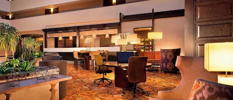 A spacious lobby with a high ceiling, multiple seating areas, and a patterned carpet.