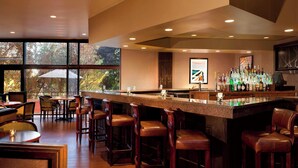 A bar area with a long counter, multiple stools, and a bar stocked with bottles.