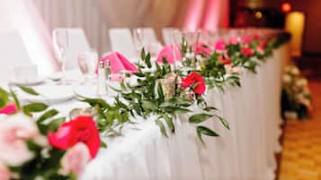 A table set with white tablecloths, pink napkins, and floral centerpieces.