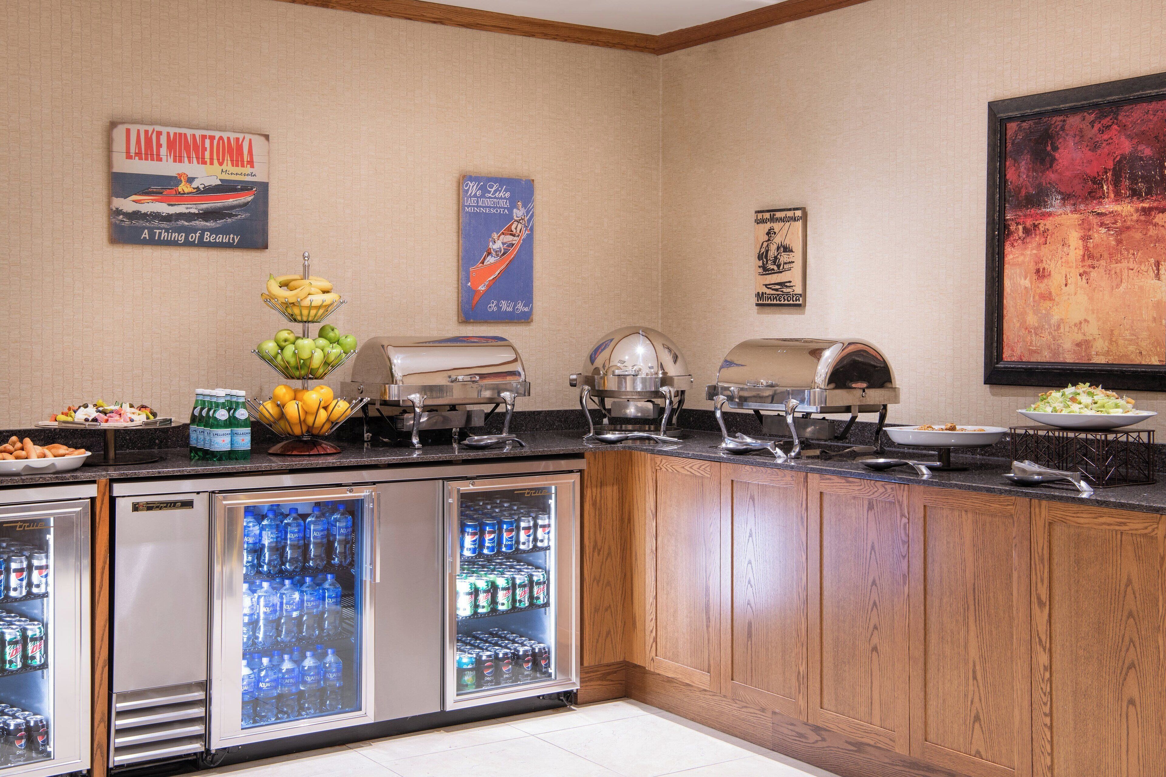 A buffet setup with a refrigerator, a fruit bowl, and various food items.