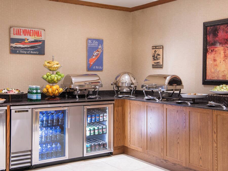 A buffet setup with a refrigerator, a fruit bowl, and various food items.
