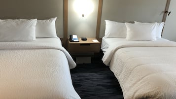 Ein Hotelzimmer mit zwei Betten, einem Nachttisch mit Telefon und Uhr sowie einer Wandleuchte.