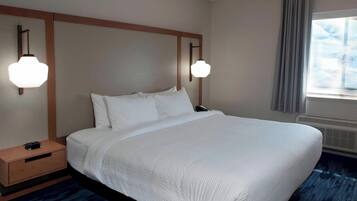 Una habitación de hotel con una cama grande, cabecera de madera, mesitas de noche y dos lámparas fijadas a la pared.