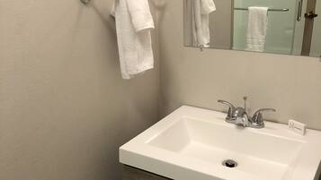 Une salle de bain avec un lavabo blanc, un miroir et deux serviettes suspendues à des porte-serviettes.