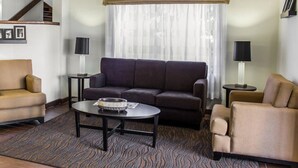 A modern living room with a sofa, armchairs, a coffee table, and two lamps. A staircase is visible in the background. - Sleep Inn & Suites Spring Lake - Fayetteville near Fort Bragg (Spring Lake)