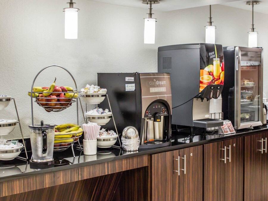 Una estación de café con una máquina de café, fruteros y un dispensador de bebidas.
