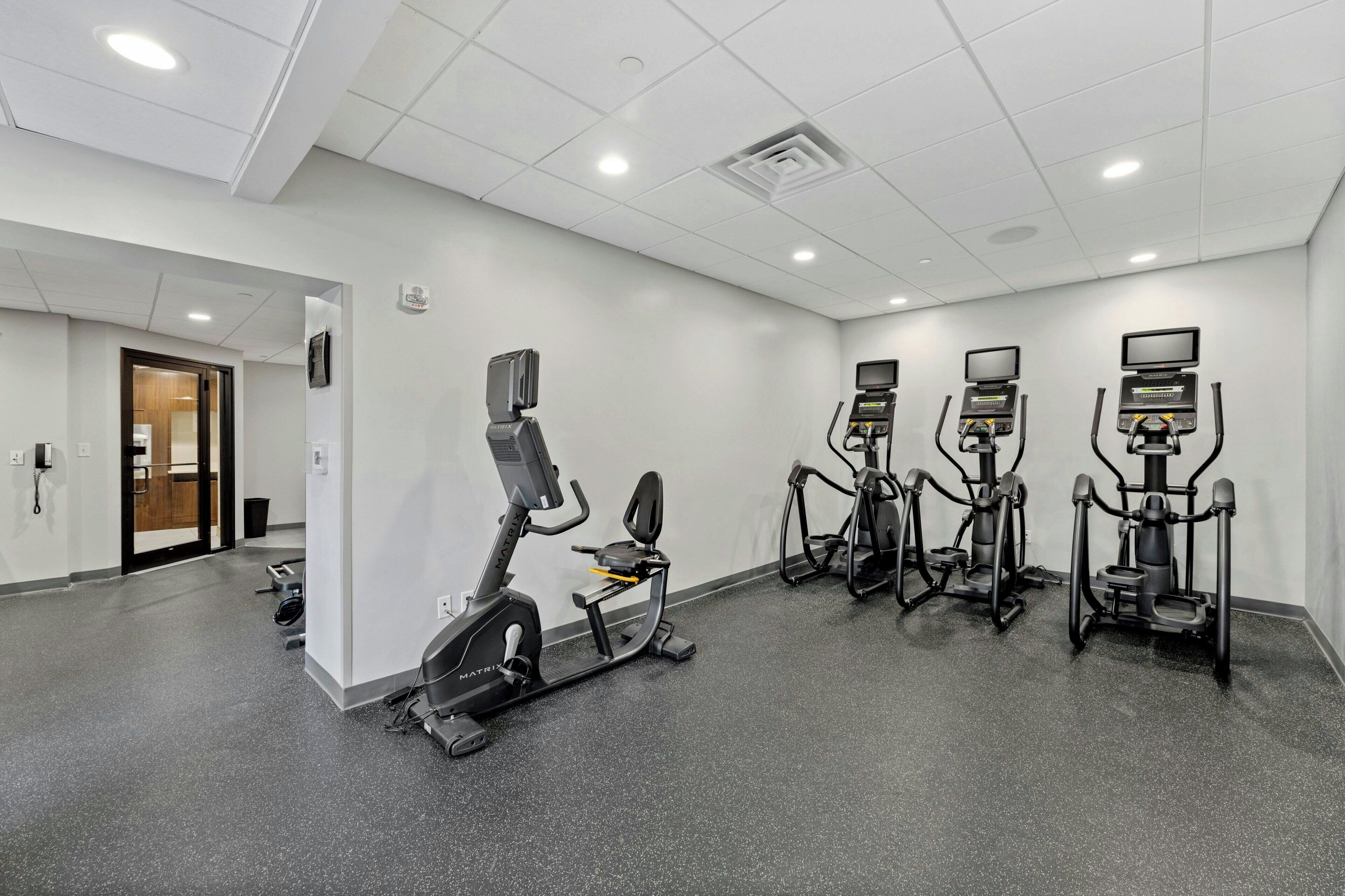 Centro de fitness com esteiras, elípticos e bicicletas ergométricas, equipado com telas digitais.