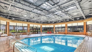 An indoor swimming pool with a tiled floor, a metal roof, and large windows.