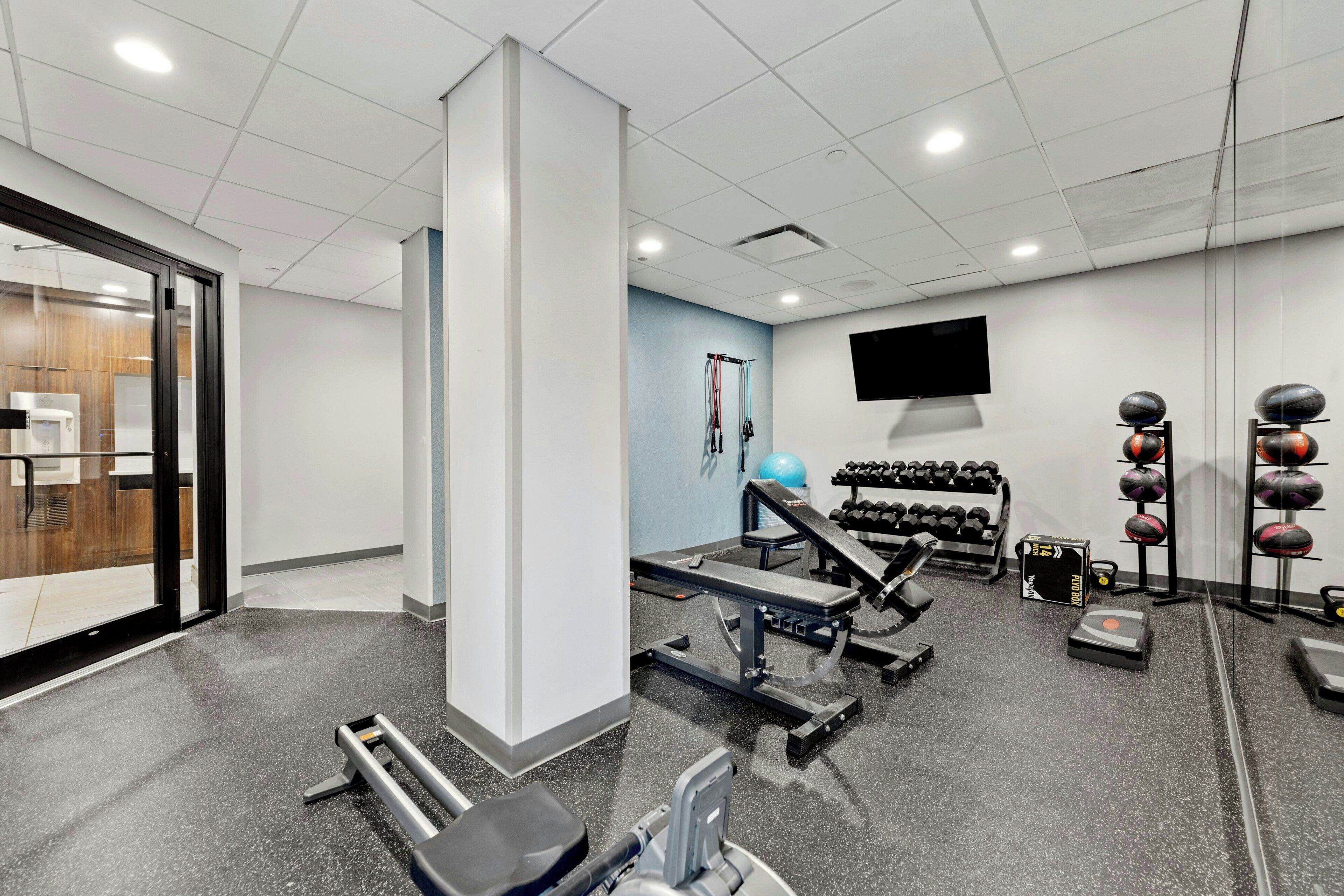 A gym with exercise equipment, a television, and a wall-mounted TV.